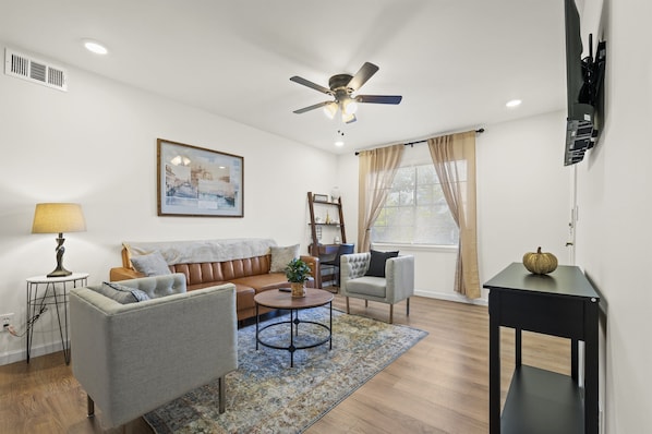 Welcome to a cozy and inviting living room designed for relaxation and entertainment. This space features a luxurious sofa that promises comfort and style, complemented by a set of plush, upholstered chairs that create a perfect spot for unwinding.