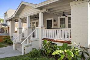 This charming property features a duplex each unit adorned with its own unique design and color palette. Nestled under a clear blue sky, these inviting houses include cozy porches and are partially enclosed and equipped with games (like foosball!)