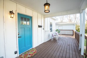 Charming front porch with a bright blue door and seating to enjoy your morning coffee or evening breeze.