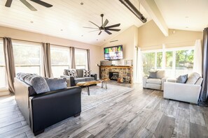Spacious living room with fireplace, ample seating, ceiling fans, and blackout curtains.