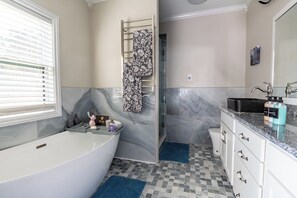 Luxurious master bathroom with soaking tub, heated floors, towel rack, large shower, and dual vanities.