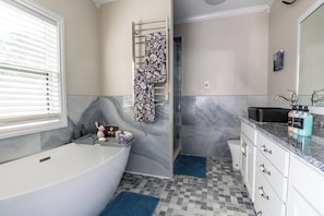 Luxurious master bathroom with soaking tub, heated floors, towel rack, large shower, and dual vanities.