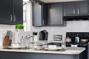 Fully equipped kitchen with granite countertops, dark cabinets, and modern appliances.
