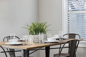 Close-up of the dining table, set for four, with elegant dishware and a touch of greenery.