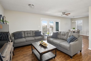 Bright and spacious living room with two cozy gray sofas, a coffee table, and plenty of natural light.
