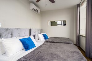 Cozy double-queen bedroom with a ceiling fan, plush bedding, and elegant decor for a restful stay.