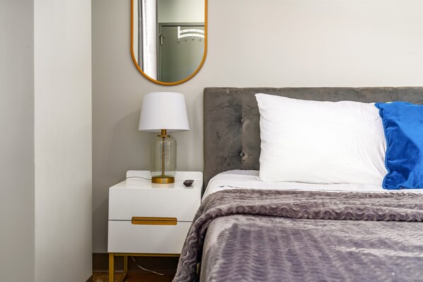 Cozy bedroom with modern decor, plush bedding, and stylish bedside lighting.