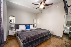 Spacious bedroom with soft bedding, a ceiling fan, and an inviting ambiance.