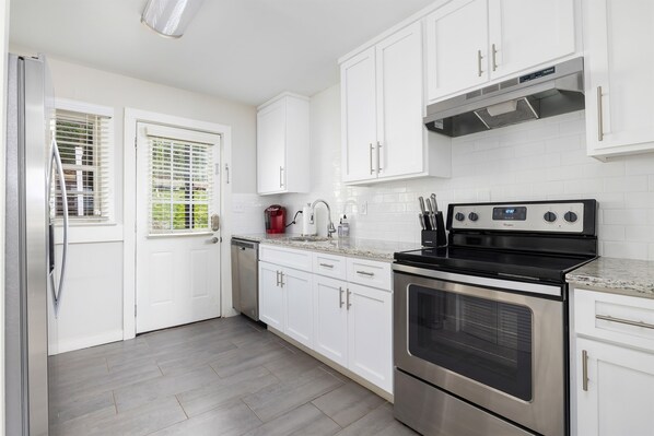 Modern kitchen with stainless steel appliances, white cabinetry, and granite countertops. Fully equipped for preparing your favorite meals.