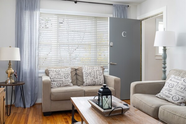 Welcome to unit C at Vulcan View! One of the two upstairs units, with bright and spacious living room in Unit C, featuring cozy seating, a smart TV, and soft curtains for added comfort.