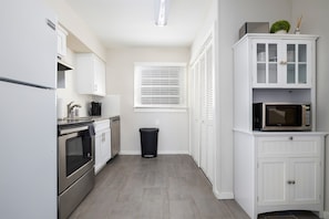 Unit D’s kitchen is fully equipped with stainless steel appliances, white cabinets, and a sleek, functional design.