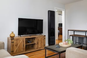 A warm and welcoming living area with a large smart TV, stylish furniture, and a cozy atmosphere, perfect for relaxing after a day of exploring.