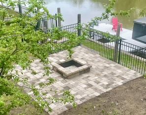 Fenced in backyard with firepit next to waterfront and dock.