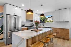 A modern kitchen outfitted with everything you could need: airfryer, juicer, blender, toaster, coffee maker, and chef's stove and oven