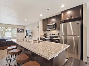 Full kitchen with sink in-island and bar seating.