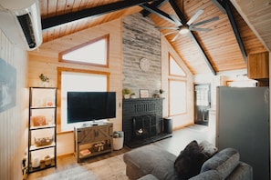 Cozy & Spacious Living Room – Vaulted ceilings, rustic wood beams, a beautiful electricfireplace, 55" Smart TV w/Roku, & ceiling fan create a warm and inviting atmosphere. Stay comfortable year-round w/ the AC/heat unit in this open-concept retreat.