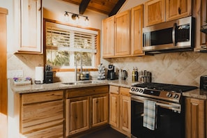 Modern Cabin Kitchen – New cabinets, granite countertops, stainless-steel gas stove/oven, microwave, fridge/freezer enhances meal prep with style and function.