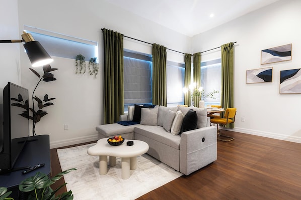 Living room with 50" Smart TV and slide out sleeper sofa w/ bedding.