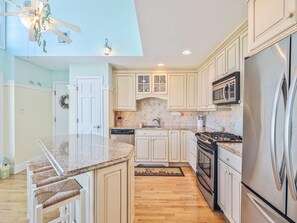 Whip up family meals in this elegantly designed kitchen featuring ample counter space and modern appliances, set against a backdrop of sea greens and sandy hues reminiscent of the coast.