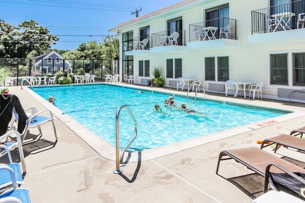 Families relax in the spacious outdoor pool area, complete with lounge chairs and sunny skies, ideal for quality time.