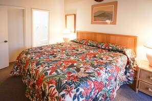 This vibrant master bedroom features a cozy king bed adorned with tropical floral prints, providing a serene retreat just steps from the ocean.