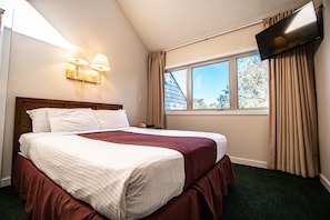 This cozy bedroom features a queen bed, natural light from large windows, and modern decor, perfect for family relaxation after a day of fun.