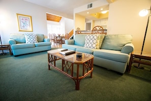 Experience comfort in this spacious Sandcastle Village II townhouse, featuring a cozy living area with plush seating and a welcoming atmosphere ideal for family gatherings.