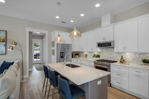 Sleek kitchen with a breakfast bar, stainless appliances & pendant lighting.