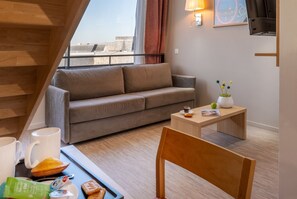 This inviting space showcases a grey sofa, a wooden coffee table laden with snacks, and a warm atmosphere from the lighting.