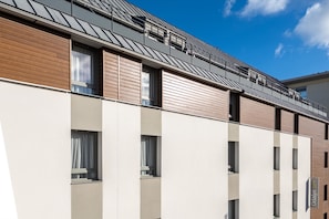 The building's clean lines and minimalistic façade highlight a blend of urban sophistication, with large windows allowing natural light to flood into the stylishly arranged apartments.