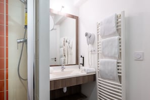 The elegant bathroom is a perfect blend of functionality and modernity, showcasing a clean design with warm lighting, a spacious vanity, and a refreshing shower, ensuring a rejuvenating experience.