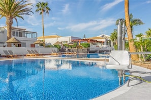 Sunlit pool deck with inviting crystal-clear waters, framed by a stunning vista.