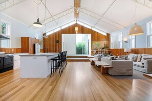 Huge, cathedral ceilings engulf the open-plan living, dining, kitchen areas