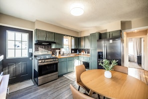 The eat in dining table, perfect for gathering and enjoying meals. You’ll also see the large refrigerator with plenty of room for your groceries and a stairwell leading down to the cozy family room.