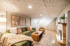 The cozy basement family room is perfect for relaxing, with a plush sofa, swivel chair, and the warm glow of an electric fireplace. Enjoy streaming on the smart TV in this comfortable retreat designed for everyone to unwind.