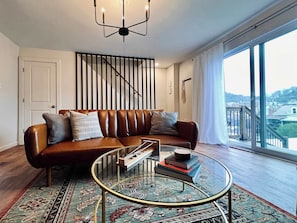 LIVING ROOM | FIRST FLOOR: Enjoy the natural light from the sliding glass doors! The interior door leads down to the basement with a washer & dryer and complimentary detergent and dryer sheets, while the stairs go up to the second floor.
