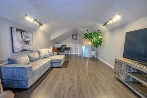 Bonus room above garage with smart tv, office desk, and comfy couch! This room is perfect for those chilly winter nights to curl up and watch tv or get some work done.