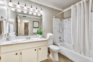 A bright and spacious bathroom featuring a large vanity, soft lighting, and a relaxing tub-shower combination for ultimate comfort.
