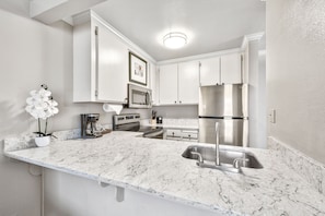 Sleek countertops and a well-appointed layout make this kitchen a delightful place to enjoy your morning coffee or cook up something special.