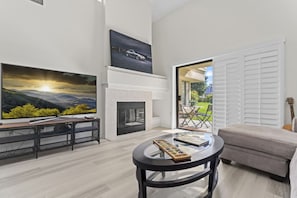 Bright living room with cozy fireplace, modern TV setup, and patio access