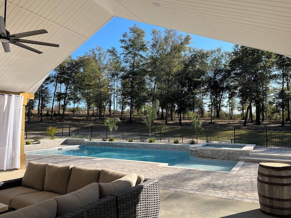 Backyard covered space with seating, pool and hot tub