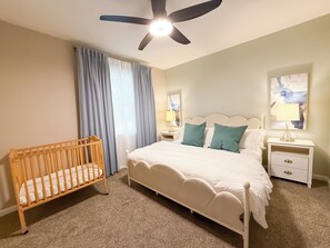 Primary Suite: King bed, blackout curtains, portable crib and office space.
