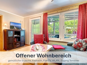 Offener Wohnbereich mit gemütlichen Sitzmöbeln und Flat-TV.