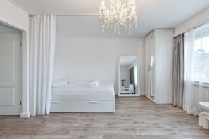 Spacious and serene, the bedroom area boasts natural light and a soothing white color scheme.