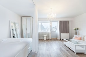 Spacious, light-filled studio with soft curtains dividing the sleeping area from the stylish living space.