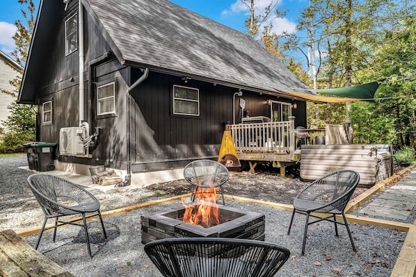 Take in the expansive view of our backyard, featuring a cozy firepit surrounded by woven chairs, a spacious deck with a grill, and a relaxing outdoor hot tub — your private oasis for unforgettable gatherings and relaxation!