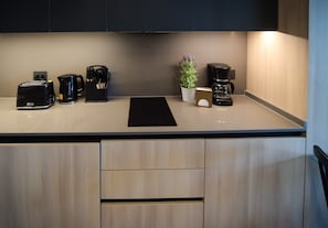 Modern kitchen with sleek appliances and a touch of greenery, perfect for preparing meals during your stay.