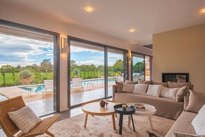 Expansive lounge area with panoramic windows framing serene golf course views—perfect for unwinding in style.