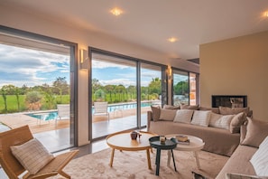 Expansive lounge area with panoramic windows framing serene golf course views—perfect for unwinding in style.