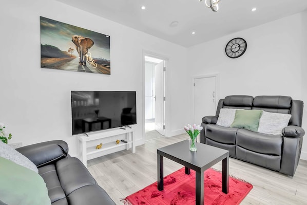 Bright living room with two plush sofas, coffee table, and Smart TV so that you can stream your favourite channels on Netflix or Prime